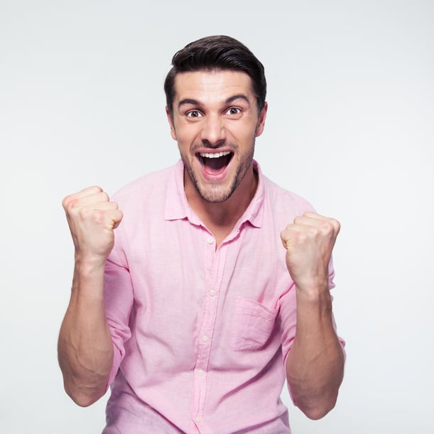 Happy businessman celebrating his success over gray background. Looking at camera